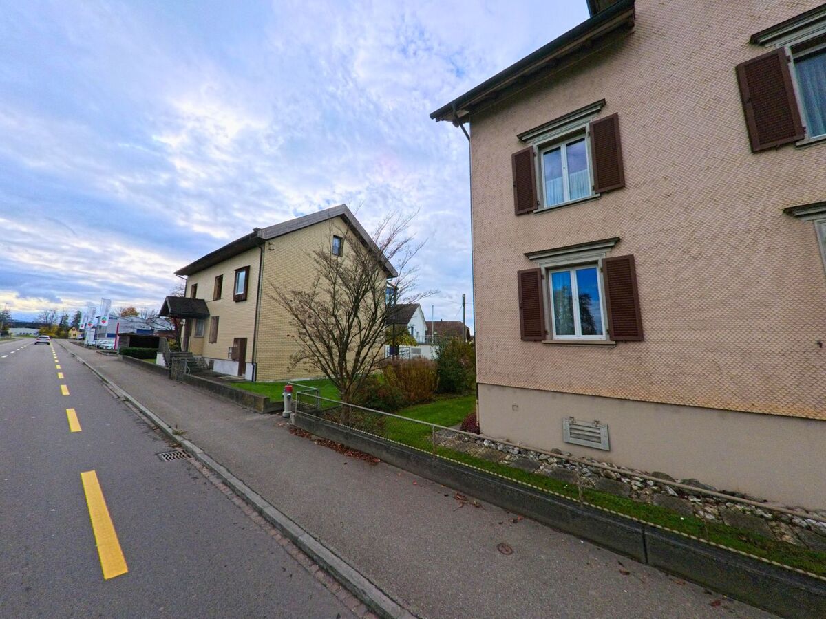 Mehrere Wohnhaeuser mit Vorgarten reihen sich entlang einer ruhigen Strasse in Salmsach (8599, Kanton Thurgau) unter herbstlichem Himmel.
