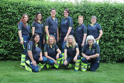 Mitglieder eines Samaritervereins stehen und knien gemeinsam fuer ein Gruppenfoto im Freien in Grossaffoltern (3257, Kanton Bern).