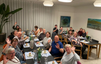 Die Mitglieder des Samaritervereins Diepoldsau-Schmitter sitzen in Diepoldsau (9444, Kanton St. Gallen) gemeinsam an gedeckten Tischen und winken in die Kamera.