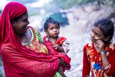 Eine Frau traegt ein Kleinkind auf dem Arm, waehrend ein Maedchen neben ihr steht; die Szene spielt sich in Zürich (8008, Kanton Zürich) auf einem schmalen Weg ab.