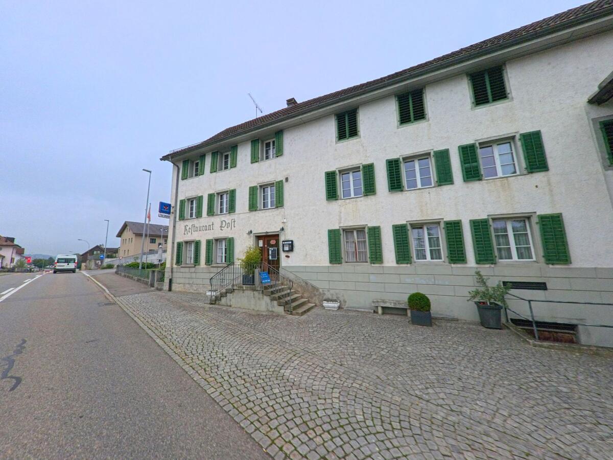 Das traditionsreiche Restaurant Post in Sarmenstorf (5614, Kanton Aargau) mit grünen Fensterläden und gepflastertem Vorplatz liegt direkt an der Hauptstrasse des Dorfes.