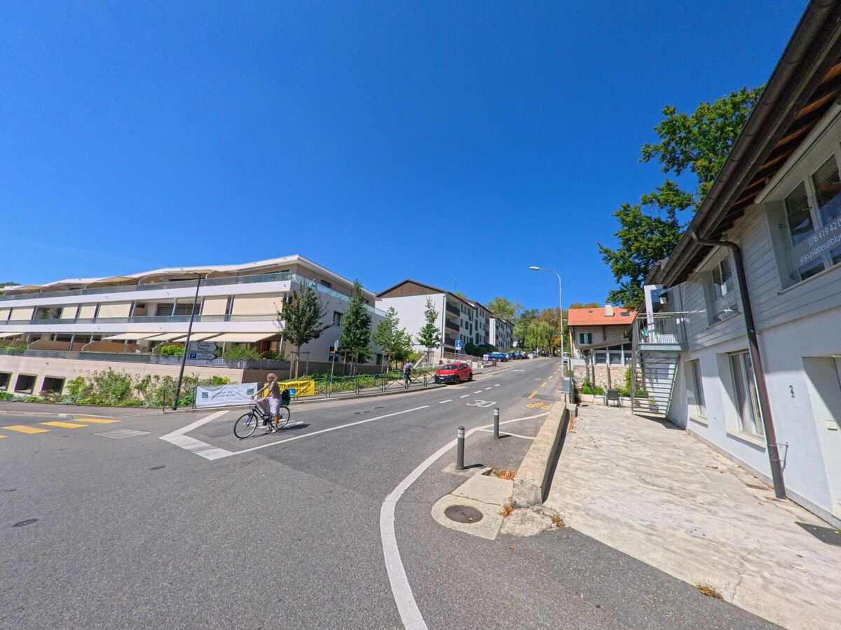 Eine ansteigende Strasse in Satigny (1242, Kanton Genf) wird von modernen Wohnbauten auf der einen und traditionellen Hausern auf der anderen Seite gesaeumt.