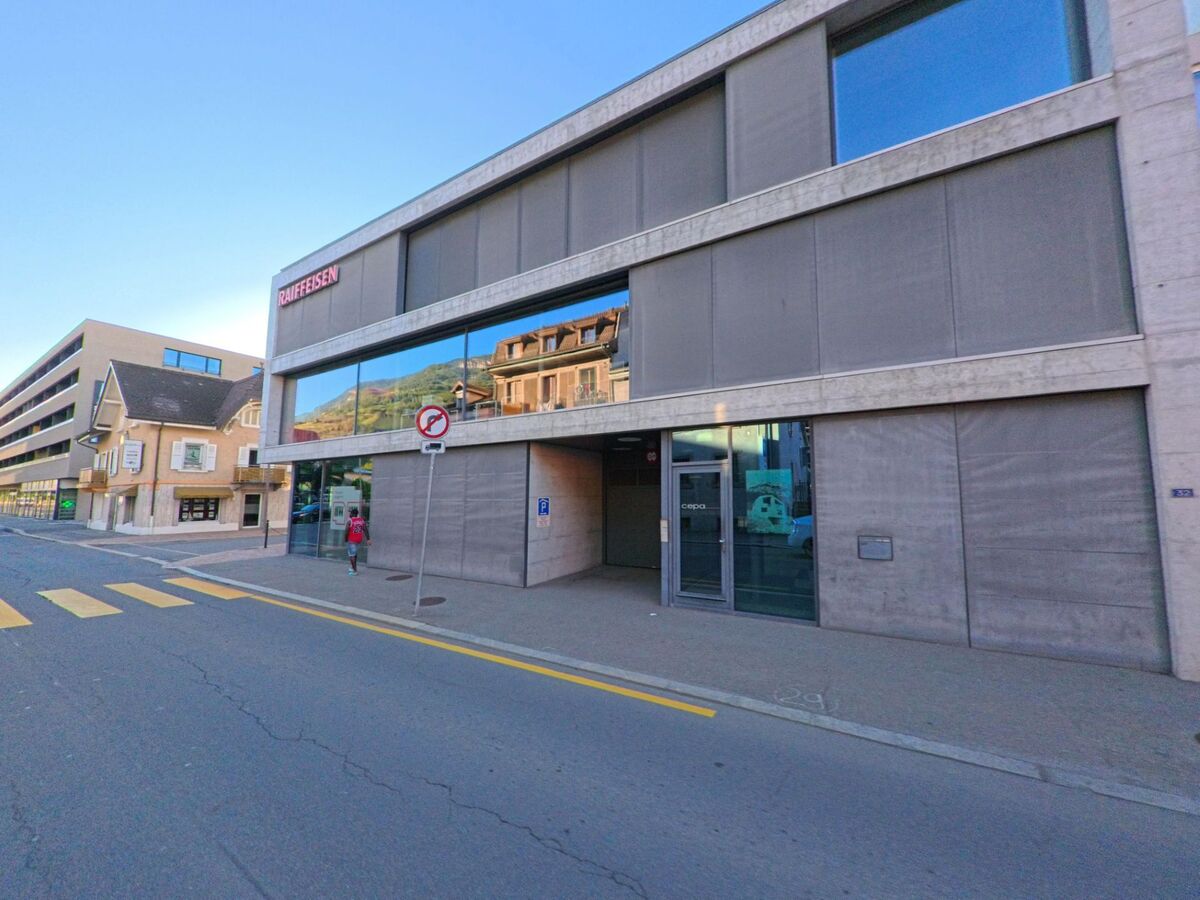 Ein modernes Bankgebaeude der Raiffeisen steht im Zentrum von Saxon (1907, Kanton Wallis) an einer Strasse mit Fussgaengerstreifen.