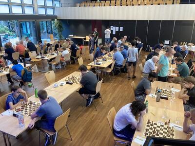 Beim Schachclub Freiamt treten in Wohlen (5610, Kanton Aargau) zahlreiche Teilnehmende an mehreren Tischen zu konzentrierten Schachpartien gegeneinander an.