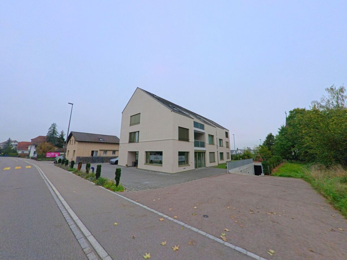 Ein modernes Mehrfamilienhaus mit heller Fassade und Tiefgarageneinfahrt steht an einer Nebenstrasse in Schafisheim (5503, Kanton Aargau).