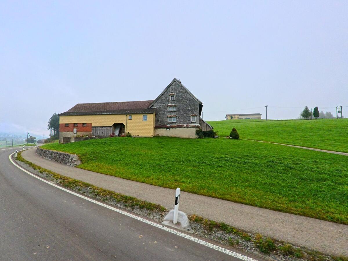 Auf einer Anhöhe liegt ein landwirtschaftliches Gebäude oberhalb der Fahrbahn in Schlatt-Haslen (9054, Kanton Appenzell Innerrhoden).