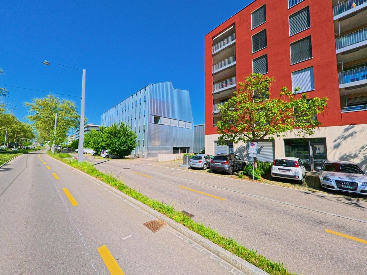 In Schlieren (8952, Kanton Zürich) verläuft ein Veloweg entlang moderner Wohn- und Geschäftsgebäude mit auffällig farbigen Fassaden.