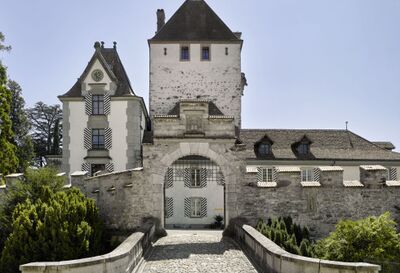 In Oberhofen (3653, Kanton Bern) fuehrt eine Steinbruecke zum Eingang des Schlosses Oberhofen mit seinem markanten Turm und den schwarz-weiss gestreiften Fensterlaeden.