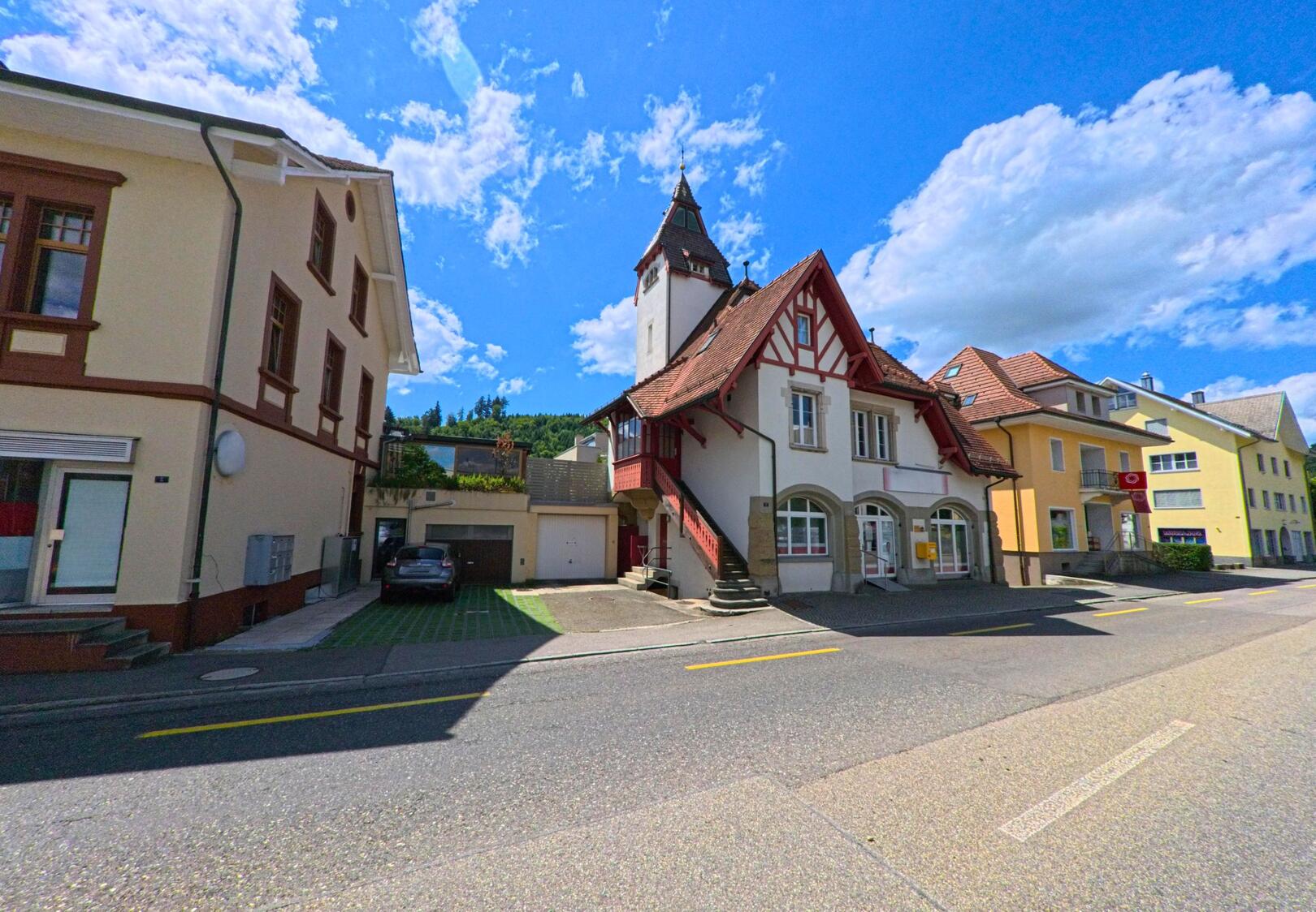 Im Zentrum von Schoeftland (5040, Kanton Aargau) steht ein markantes Gebaeude mit Fachwerkgiebel und Turm an der Hauptstrasse zwischen weiteren Wohn- und Geschaeftshaeusern.