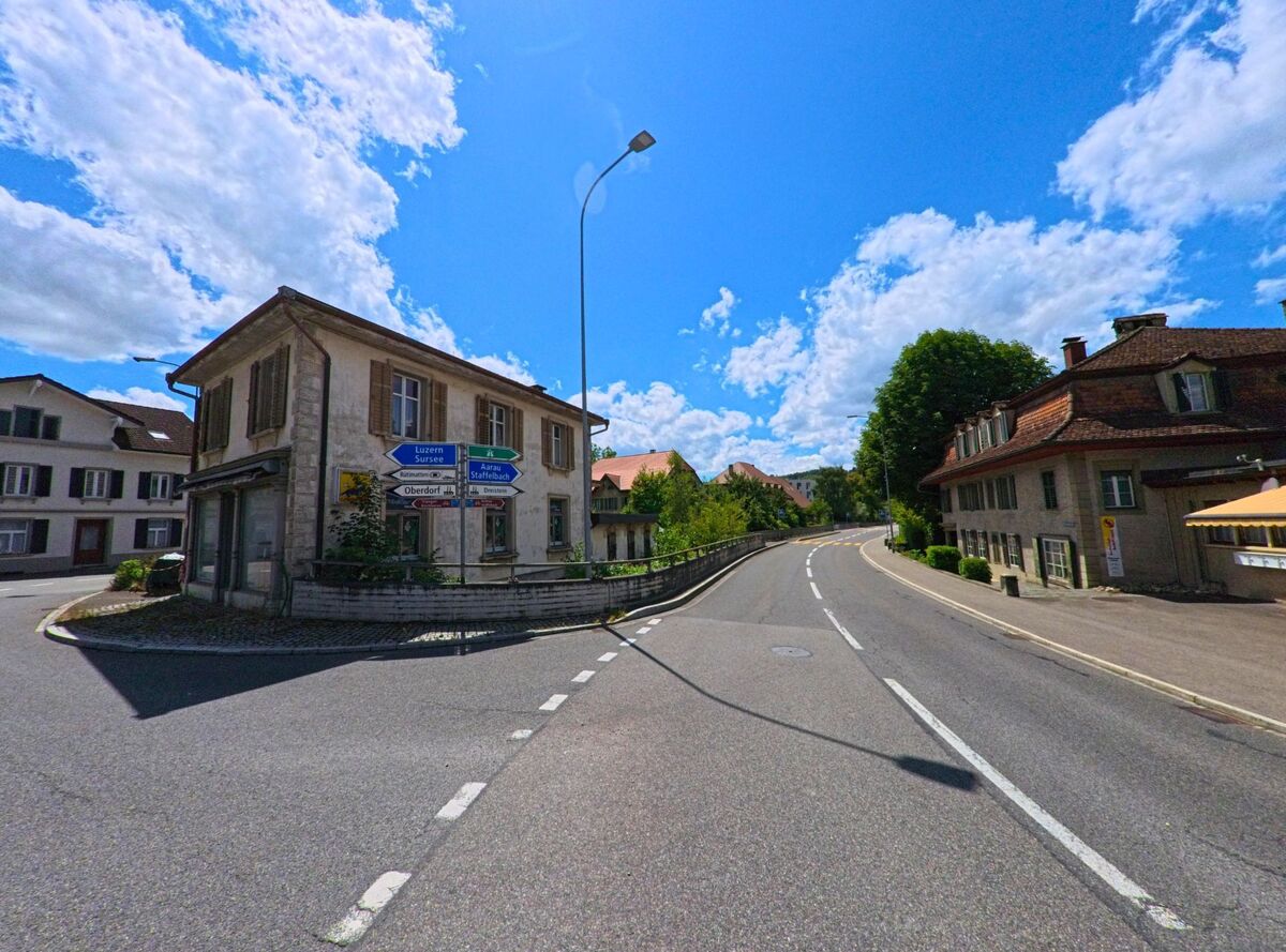 In Schoeftland (5040, Kanton Aargau) verzweigt sich die Hauptstrasse an einem Altbau mit Fensterlaeden und Wegweisern in Richtung Aarau, Luzern und Staffelbachtal.