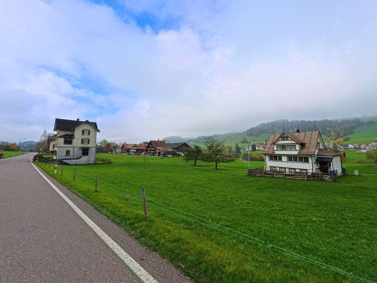 Offene Wiesen und verstreute Häuser erstrecken sich rund um Schönengrund (9105, Kanton Appenzell Ausserrhoden) unter bewölktem Himmel.