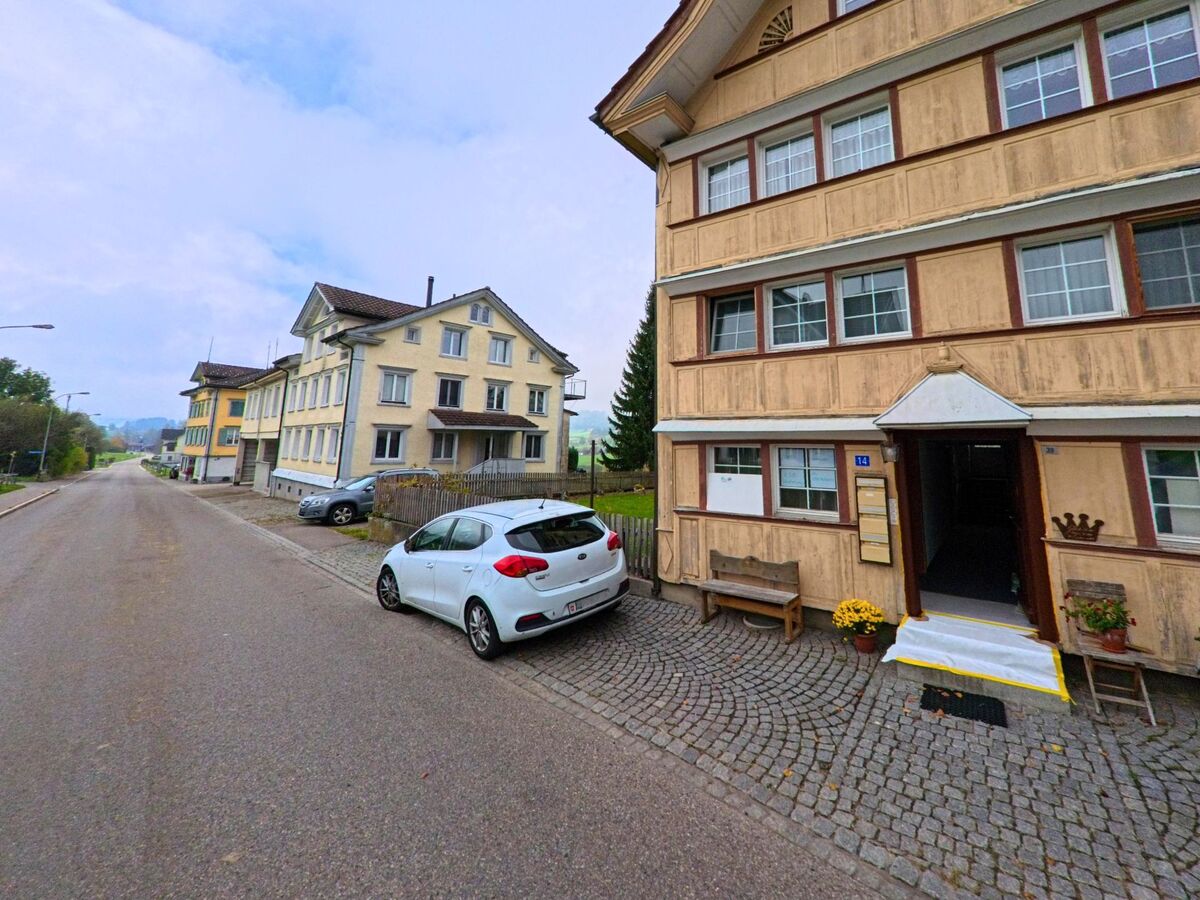Die Fassaden mehrerer Wohnhäuser prägen eine Strassenszene in Schönengrund (9105, Kanton Appenzell Ausserrhoden) mit parkierendem Auto.