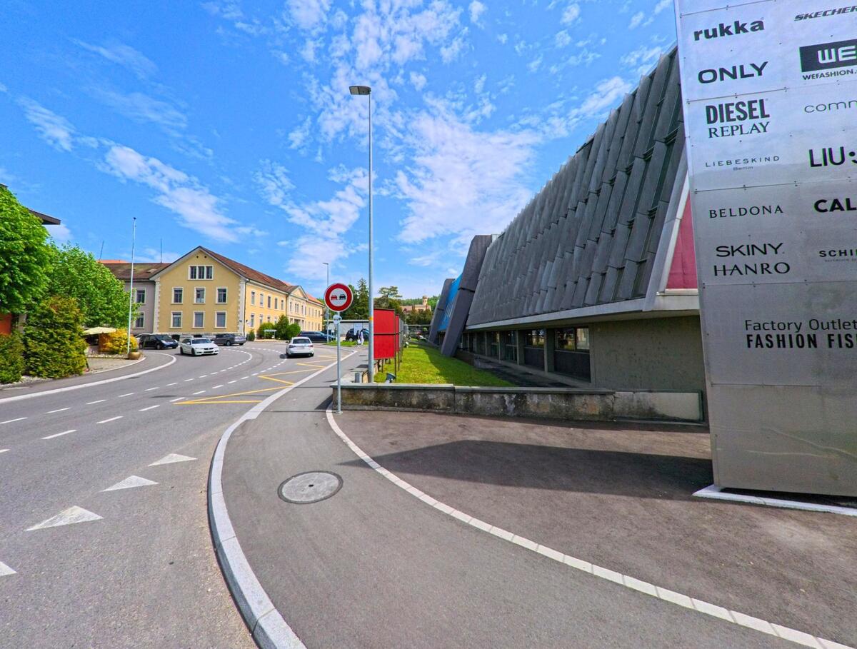 Am Eingang des Fashion Fish Outlet in Schönenwerd (5012, Kanton Solothurn) verläuft die Strasse an modernen und historischen Gebäuden vorbei.