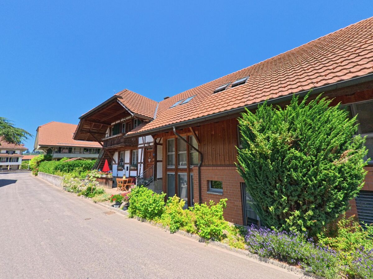 Zwei traditionelle Häuser in Schüpfen (3054, Kanton Bern), mit einem gepflegten Garten und einer gemütlichen Sitzgelegenheit vor den Eingängen.
