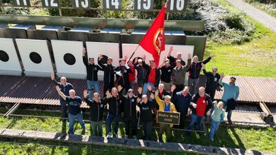Mitglieder der Schützengesellschaft Horgen (8810, Kanton Zürich) posieren fröhlich vor Zielscheiben mit Vereinsfahne und einem Schild „Bocken-Krieg 1804“.
