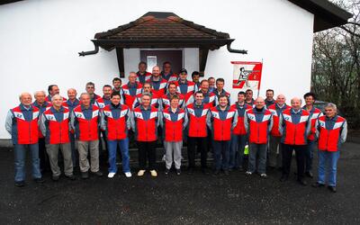 Die Mitglieder des Schützenvereins Laupersdorf posieren in roten und grauen Vereinsjacken vor dem Schützenhaus in Laupersdorf (4710, Kanton Solothurn).