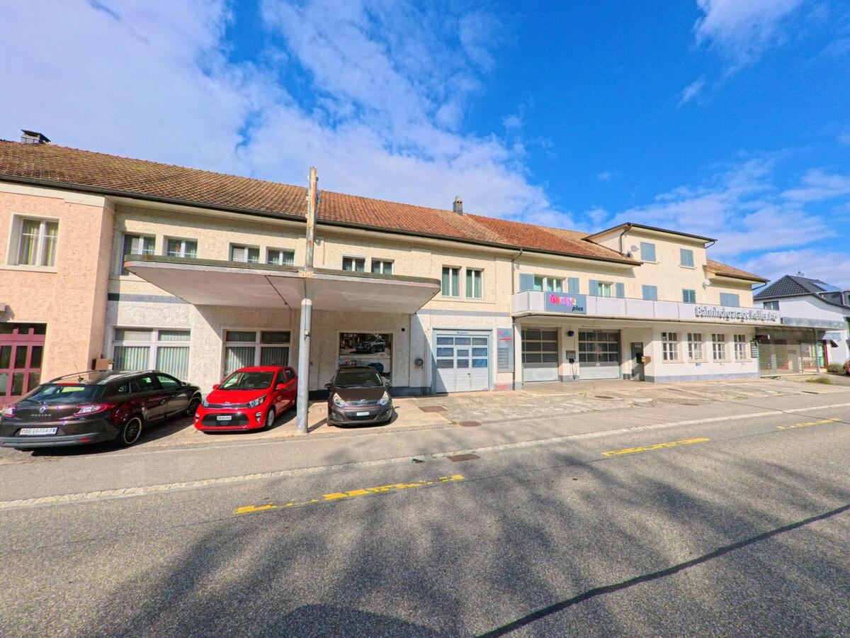 Mehrere Gebaeude mit Werkstaetten und Garagen liegen an der Hauptstrasse in Schwaderloch (5326, Kanton Aargau), wo mehrere Autos vor den Fassaden parken.