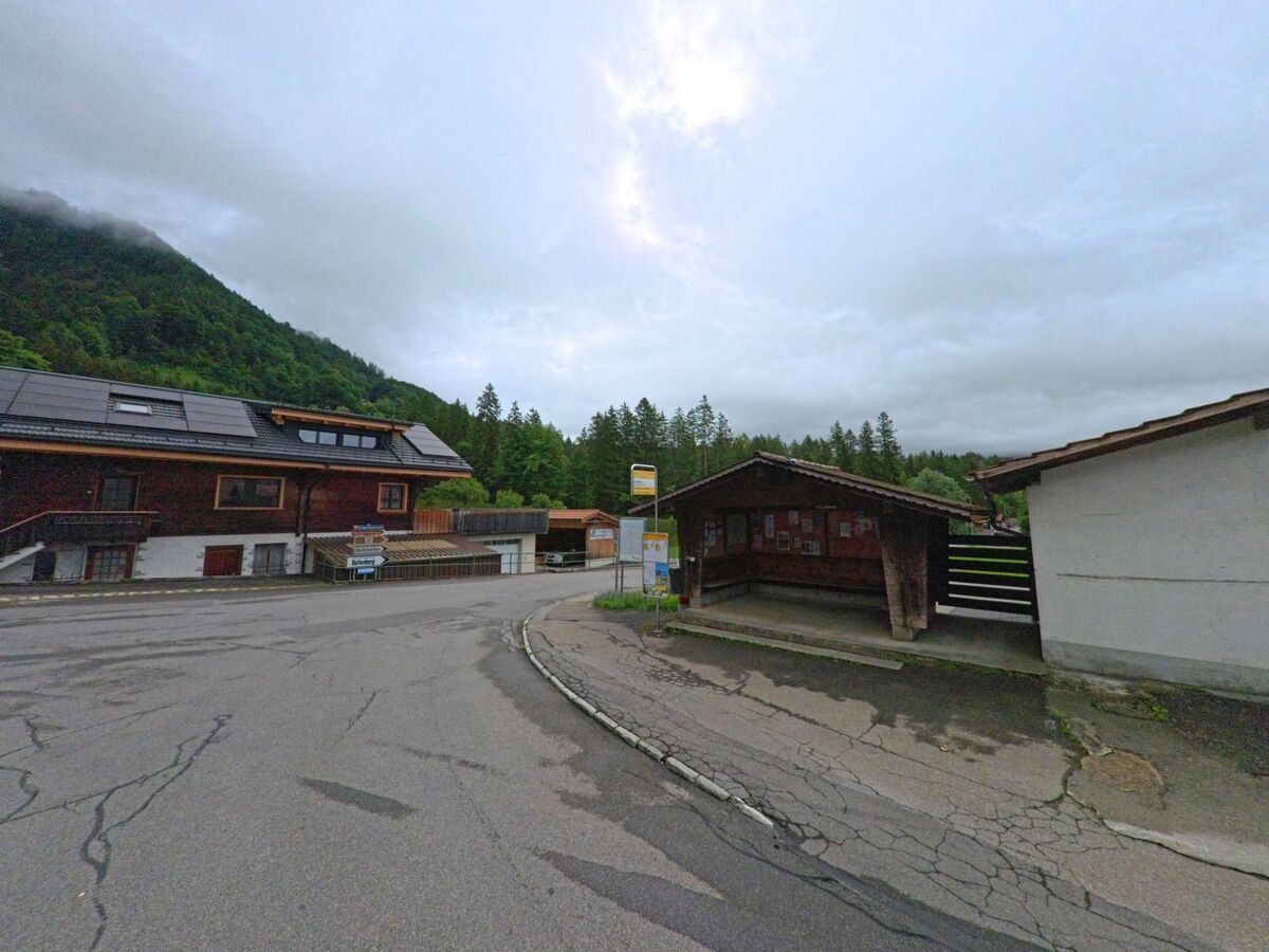 In Schwanden bei Brienz (3855, Kanton Bern) liegt eine überdachte Bushaltestelle mit Anschlagbrett an einer Strassenkreuzung am Waldrand.