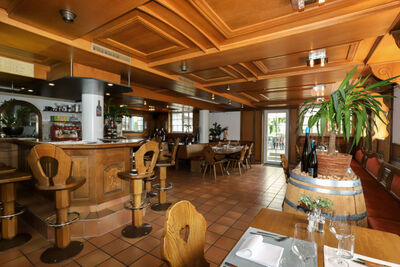 In Erlen (8585, Kanton Thurgau) zeigt das Restaurant Schwarz Delikatessen einen gemuetlichen Innenraum mit Holzbar, traditionellen Stuehlen und gedeckten Tischen.