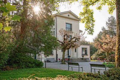Das Schweizer Strohmuseum in Wohlen (5610, Kanton Aargau) liegt inmitten eines gepflegten Parks, umgeben von alten Bäumen und sanftem Sonnenlicht.