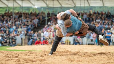 Zwei Schwinger ringen im Sägemehlring in Aarau (Kanton Aargau), während im Hintergrund zahlreiche Zuschauer das traditionelle Wettkampfgeschehen verfolgen.