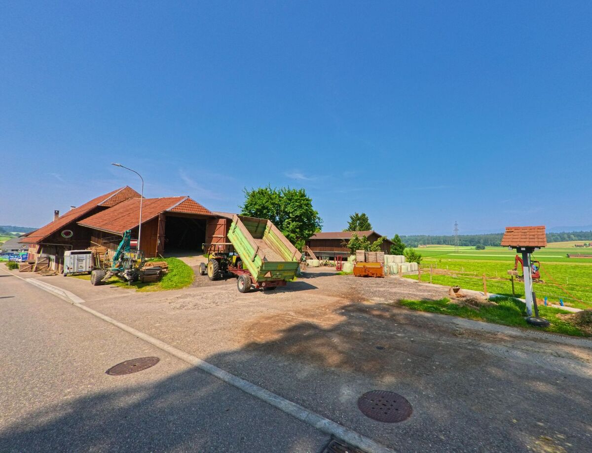 In Seeberg (3465, Kanton Bern) liegt ein landwirtschaftlicher Betrieb mit Traktoren, Scheune und Blick auf weite Felder.