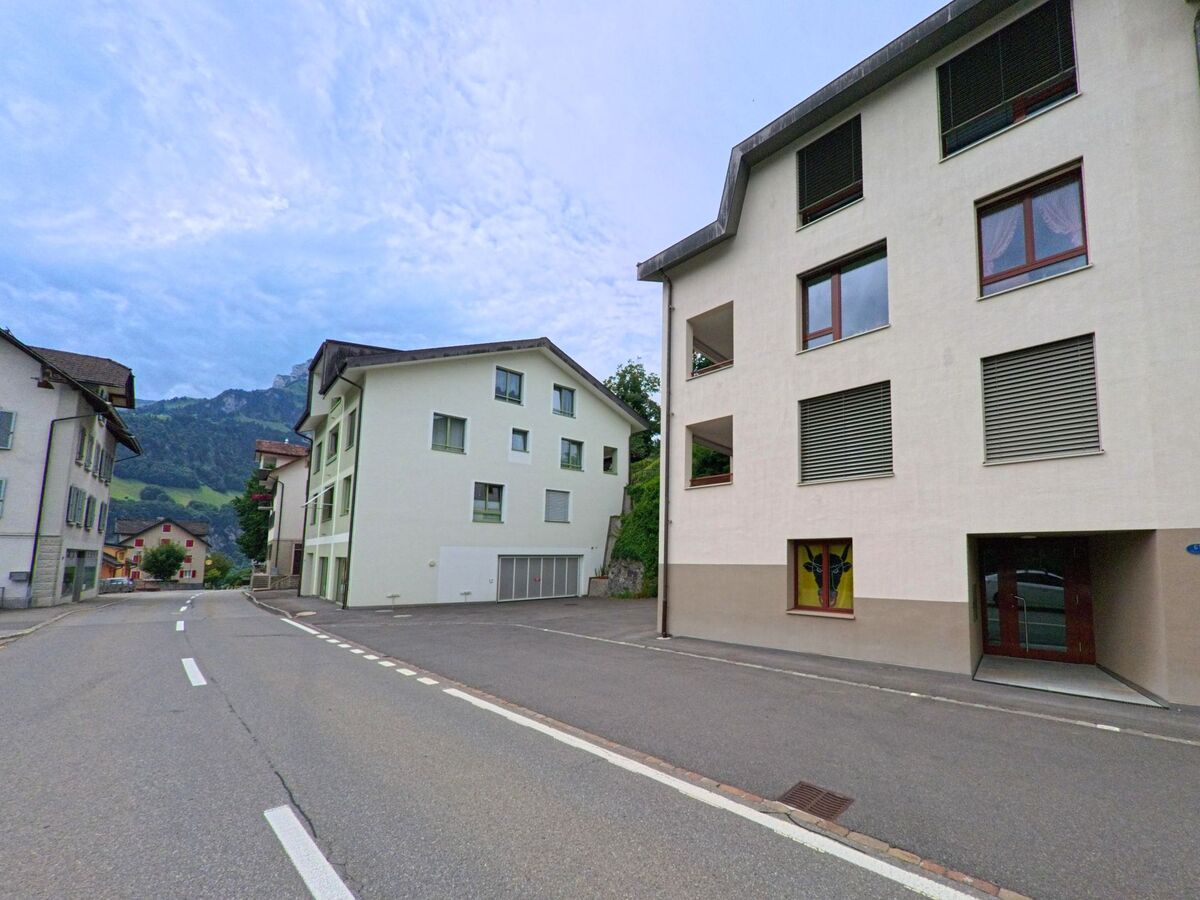 Entlang einer ruhigen Strasse in Seelisberg (6377, Kanton Uri) reihen sich moderne Mehrfamilienhaeuser vor der Kulisse der umliegenden Berge.