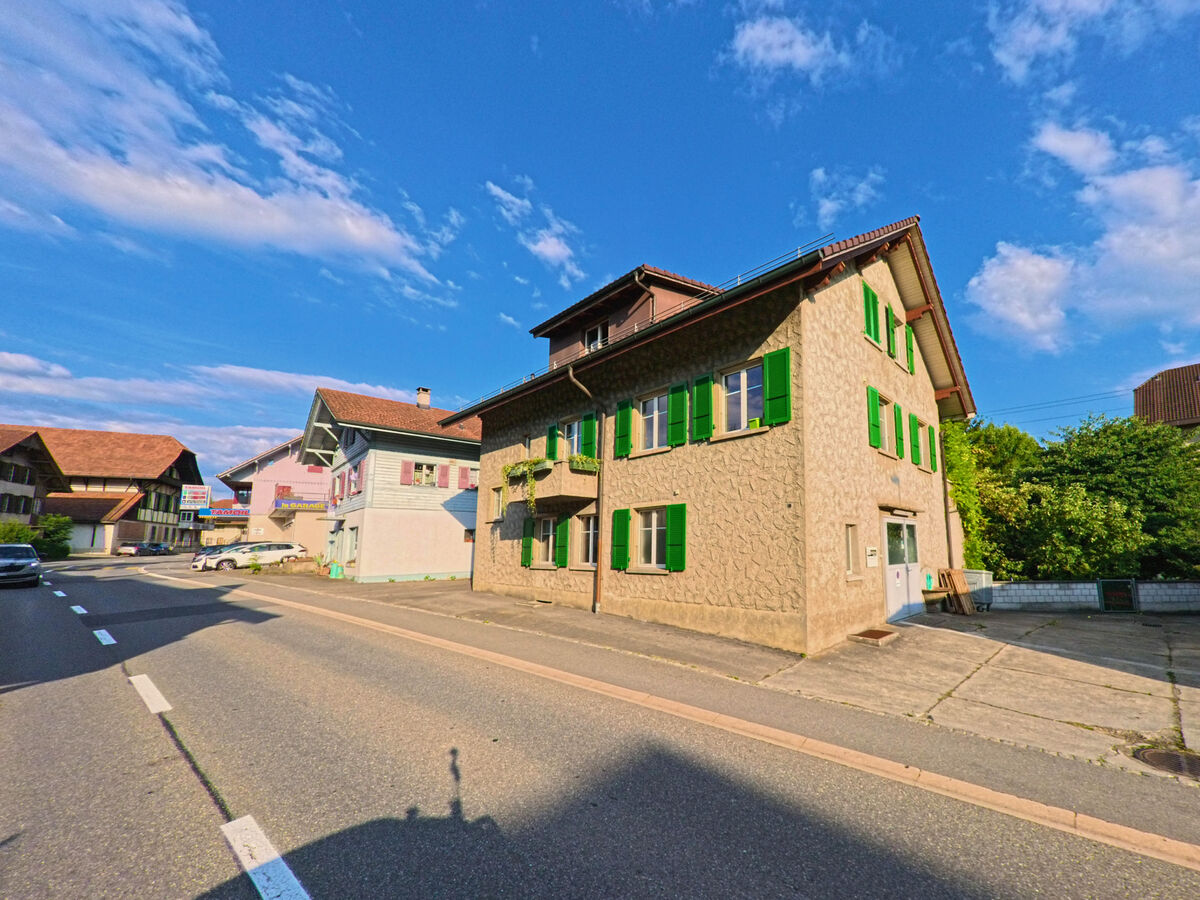 Entlang der Hauptstrasse von Seftigen (3662, Kanton Bern) stehen mehrere traditionelle Wohnhäuser, darunter ein Gebäude mit auffällig grünen Fensterläden.