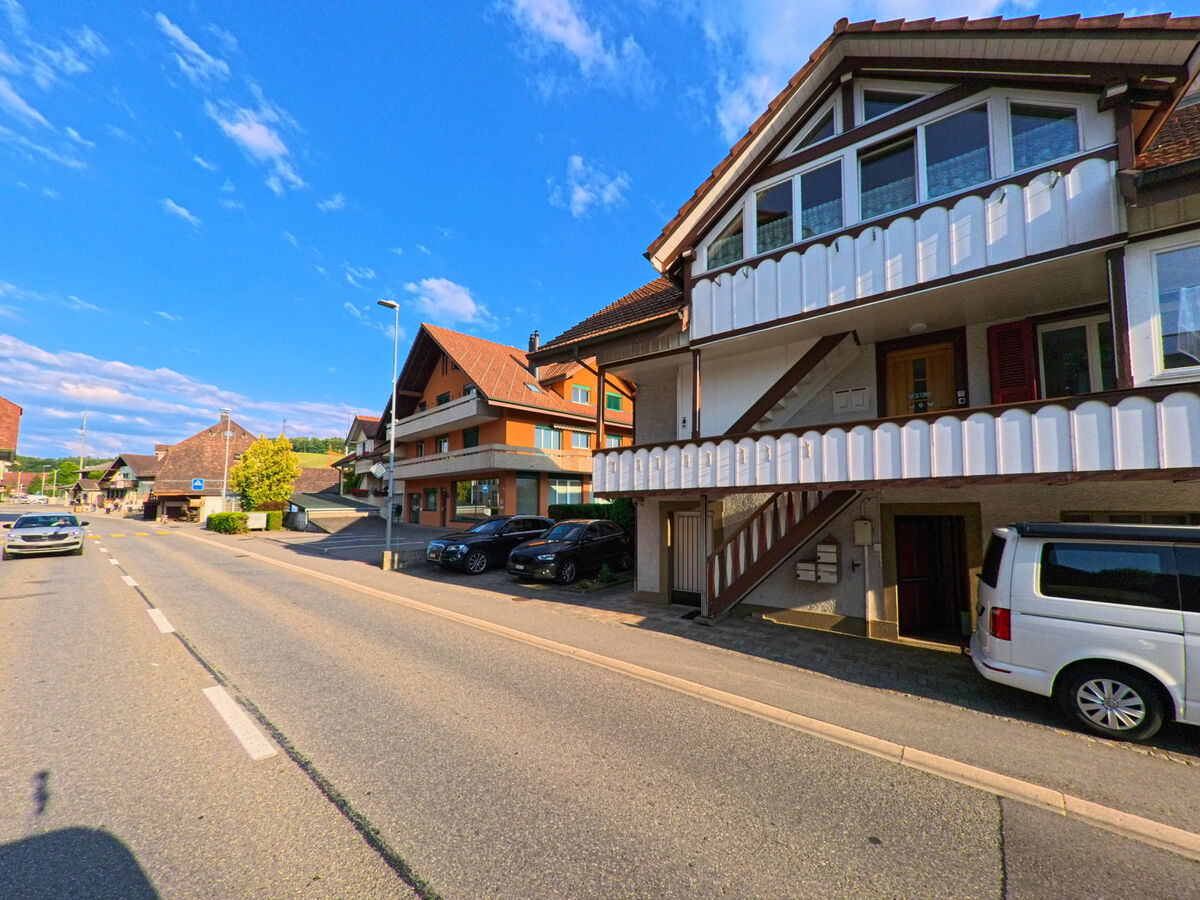 Direkt an der Hauptstrasse von Seftigen (3662, Kanton Bern) stehen Wohnhäuser mit markanten Fassaden und Parkplätzen vor den Gebäuden.
