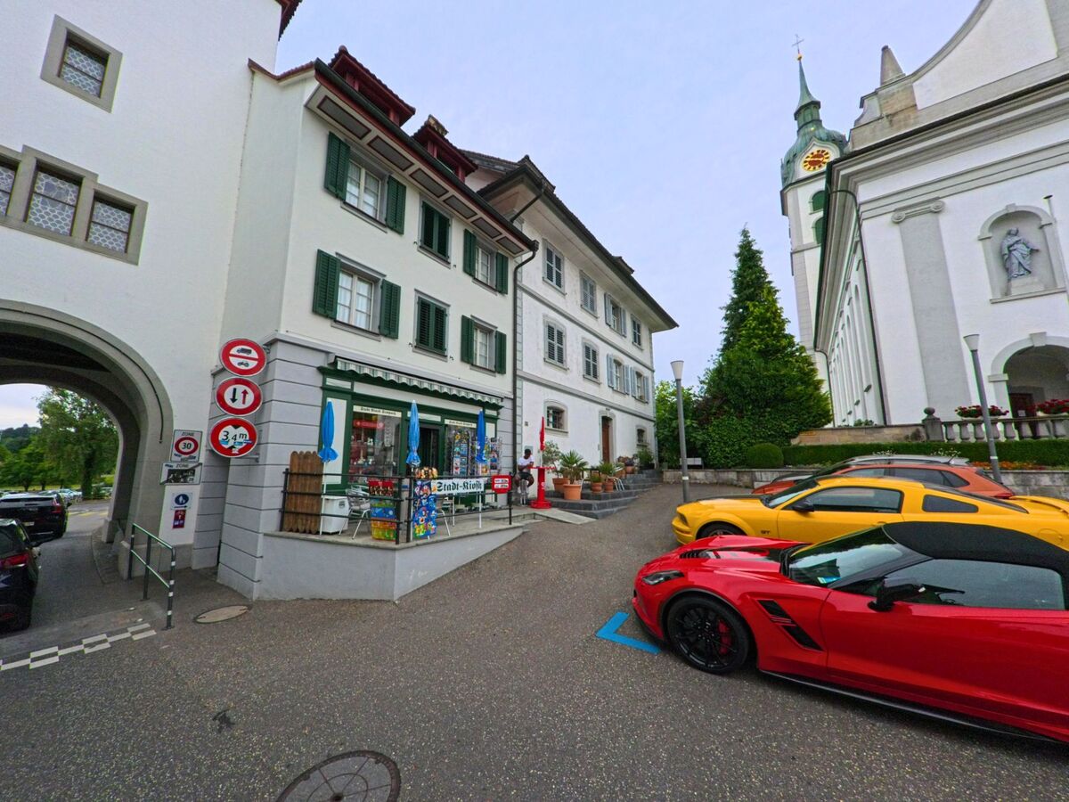 In der Altstadt von Sempach (6204, Kanton Luzern) steht ein kleiner Laden neben der Kirche, davor parken auffaellige Sportwagen in kräftigen Farben.