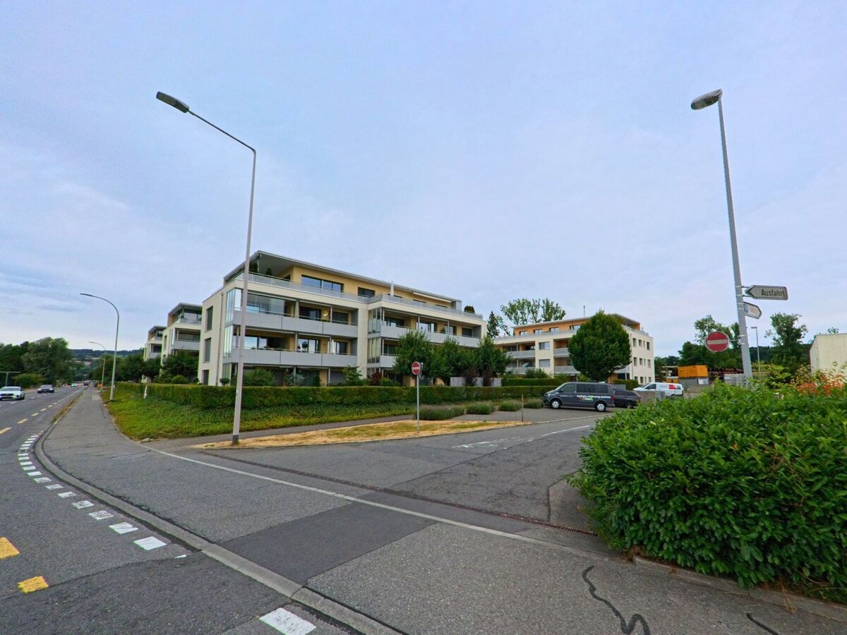 Am Ortsrand von Sempach (6204, Kanton Luzern) stehen moderne Mehrfamilienhäuser mit Balkonen entlang einer Hauptstrasse, flankiert von gepflegtem Grün.