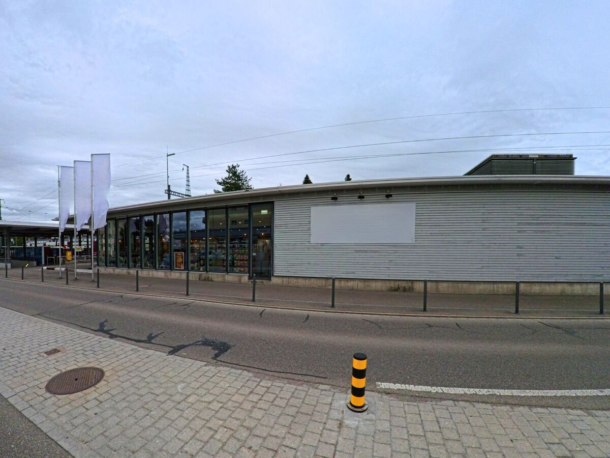 Direkt am Bahnhof von Seuzach (8472, Kanton Zürich) liegt ein modernes Verkaufsgebäude mit grossen Glasfronten und Sicht auf das Gleisfeld.