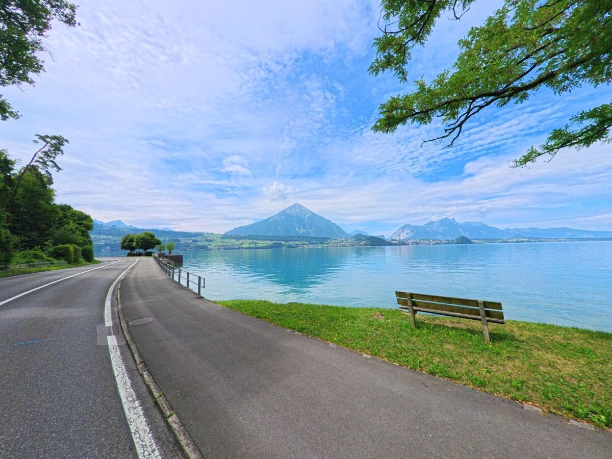 Direkt am Thunersee in Sigriswil (3658, Kanton Bern) verläuft eine Uferstrasse mit Gehweg und Sitzbank, von der aus sich ein weiter Blick auf den Niesen und die Berge bietet.