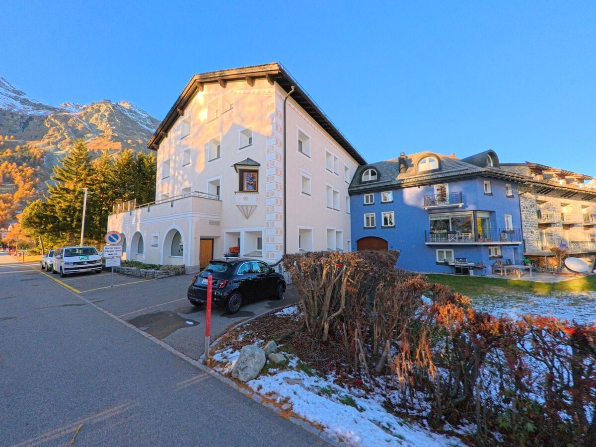 An einer ruhigen Strasse stehen gepflegte Wohnhäuser mit Gärten in Sils im Engadin/Segl (7514, Kanton Graubünden), während die tief stehende Sonne die Fassaden und die umliegenden Berge beleuchtet.