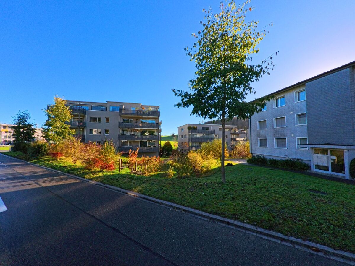 Zwischen modernen Mehrfamilienhaeusern und bepflanzten Gruenflaechen zeigt sich eine ruhige Wohnanlage in Sirnach (8371, Kanton Thurgau) bei sonnigem Herbstlicht.