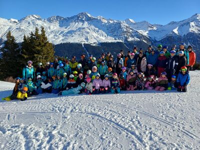 Eine grosse Gruppe des Skiclubs posiert in Gossau (9231, Kanton St. Gallen) auf verschneiter Piste vor beeindruckender Bergkulisse.