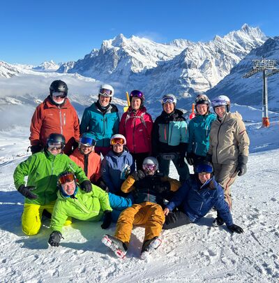 Vor einem hellen Alpenpanorama posiert der Skiclub Schenkon in Schenkon (6210, Kanton Luzern) als Gruppe in bunter Skikleidung im Schnee.