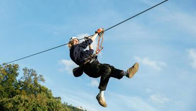 Im Seilpark Rigi in Kuessnacht am Rigi (6403, Kanton Schwyz) gleitet eine Person mit Helm und Gurt ueber eine Zipline durch die Luft.