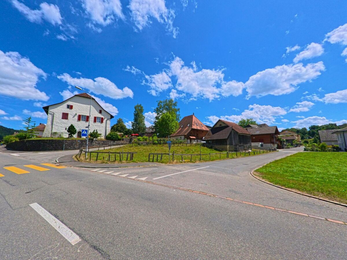Im Zentrum von Staffelbach (5053, Kanton Aargau) treffen mehrere Strassen aufeinander, umgeben von traditionellen Wohnhaeusern und Scheunen mit markanten Daechern.