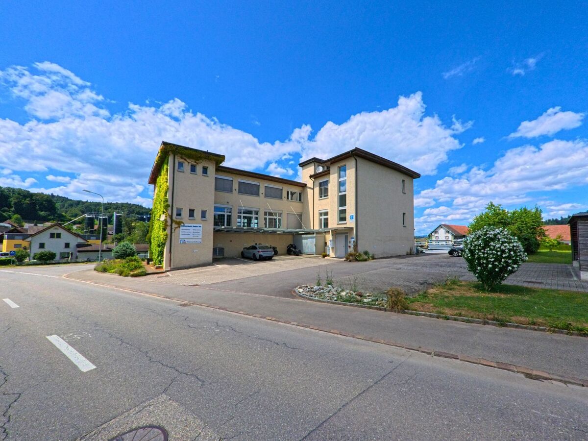 In Staffelbach (5053, Kanton Aargau) steht ein modernes Verwaltungsgebaeude mit grossem Parkplatz und begrüntem Seitentrakt an einer Nebenstrasse im Dorfzentrum.