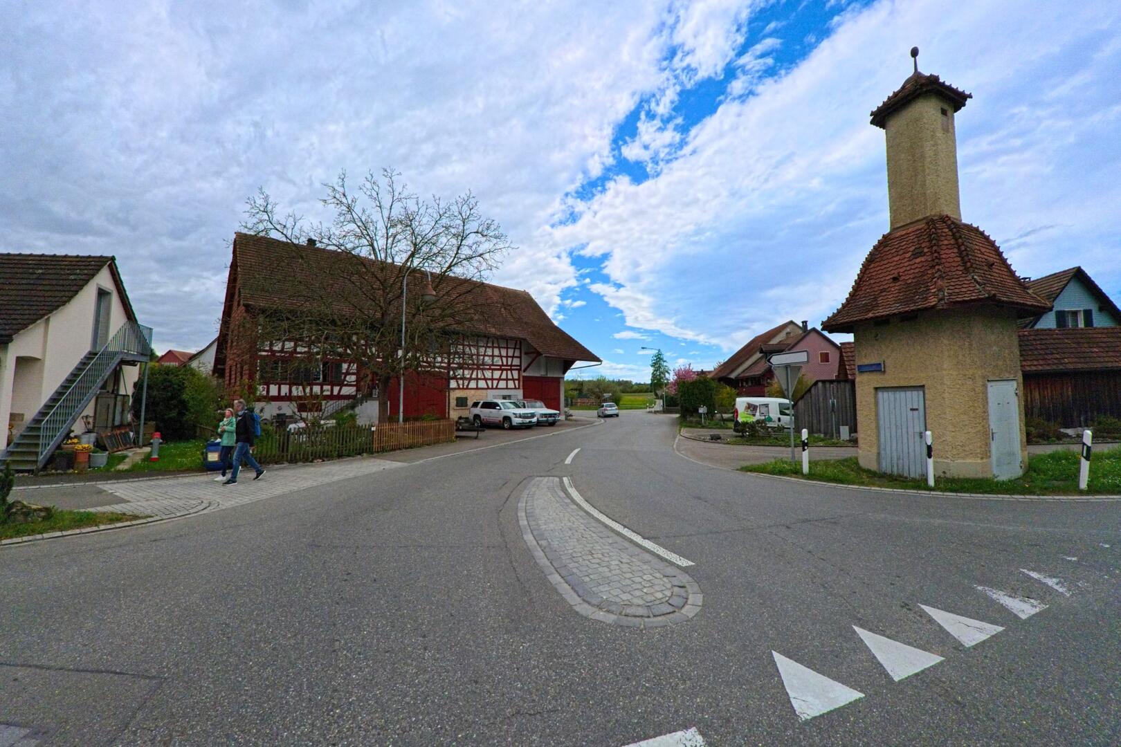 An einer Strassenkreuzung in Stammheim (8468, Kanton Zürich) steht ein markantes Fachwerkhaus neben einem historischen Gebäude mit Turmdach.