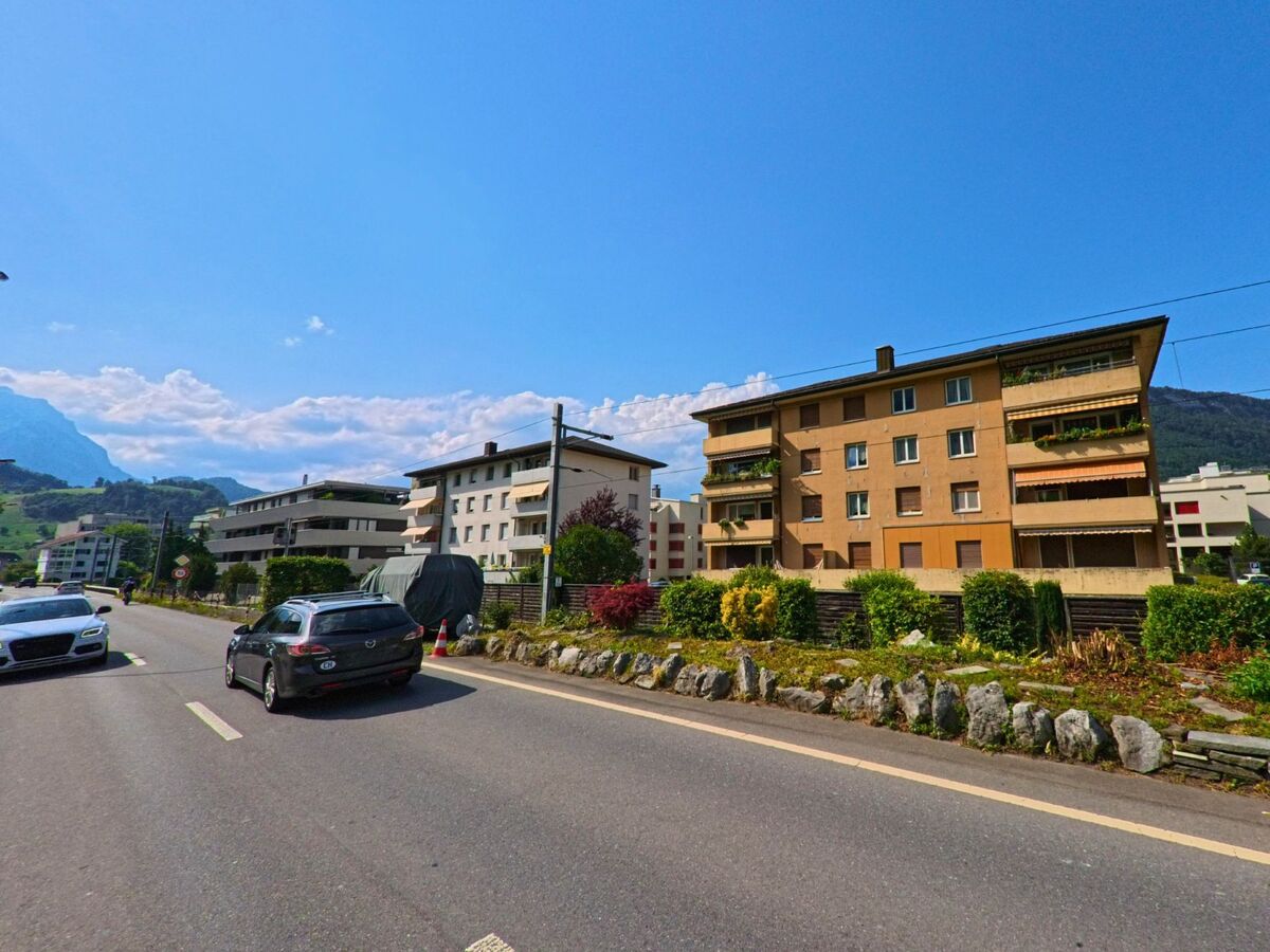 In Stans (PLZ 6370, Kanton Nidwalden) erstreckt sich eine Reihe von Mehrfamilienhaeusern entlang einer stark befahrenen Strasse, eingerahmt von Gruenanlagen und mit Blick auf die Alpen.