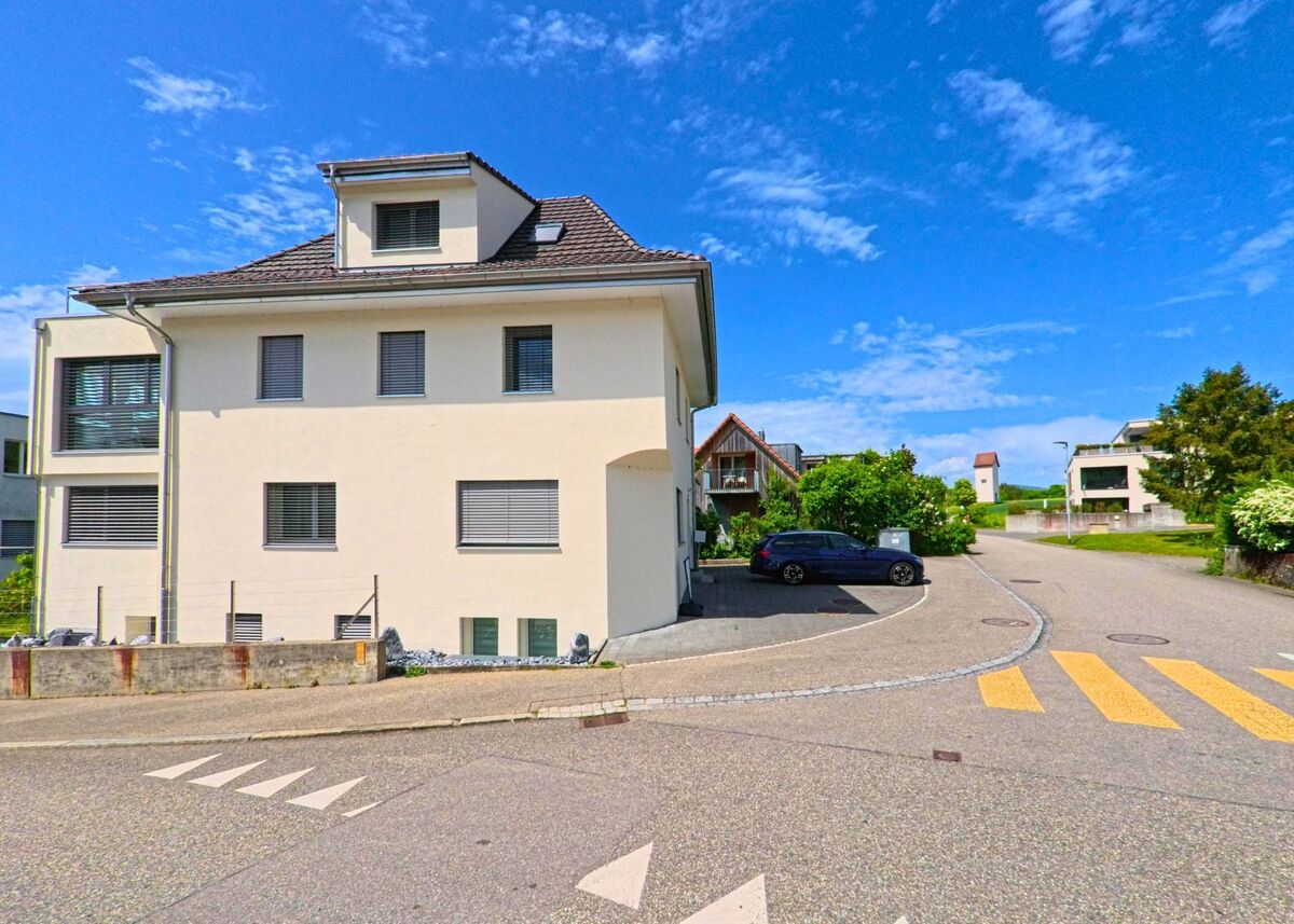 In Starrkirch-Wil (4656, Kanton Solothurn) fuehrt eine verkehrsarme Wohnstrasse an modernen Mehrfamilienhaeusern vorbei, mit gut gepflegten Gruenflaechen und Parkflaechen.