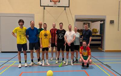 Eine Gruppe von Erwachsenen steht gemeinsam in Sportkleidung in einer Turnhalle in Bern (3007, Kanton Bern) und zeigt Teamgeist.
