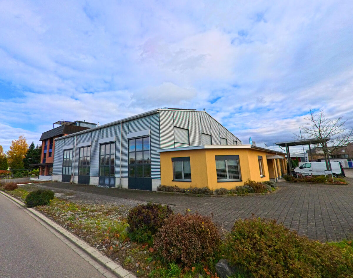 Ein modernes Industriegebaeude mit grossen Fensterflaechen liegt an einer Nebenstrasse in Steinach (9323, Kanton St. Gallen).