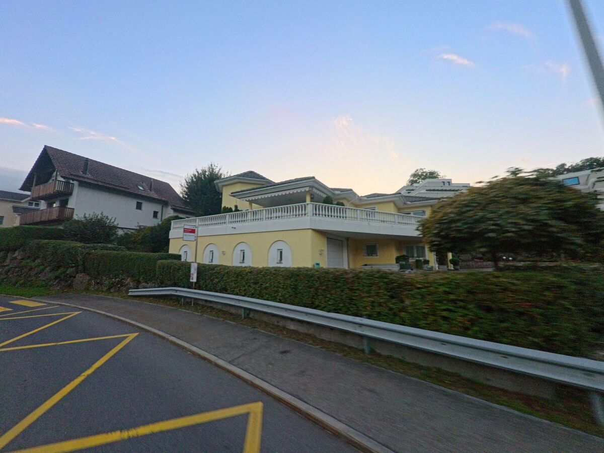Ein gelbes Wohnhaus mit grosser Terrasse liegt in Steinerberg (6416, Kanton Schwyz) leicht oberhalb der Strasse, gesaeumt von gepflegten Hecken und umgeben von weiteren Hausern.