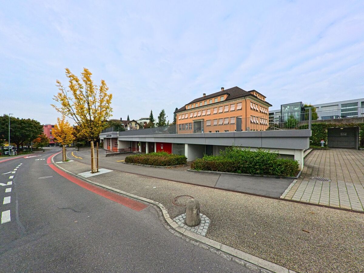 Eine Strasse mit markierter Fahrspur verläuft vor modernen Gebäuden in Steinhausen (6312, Kanton Zug).