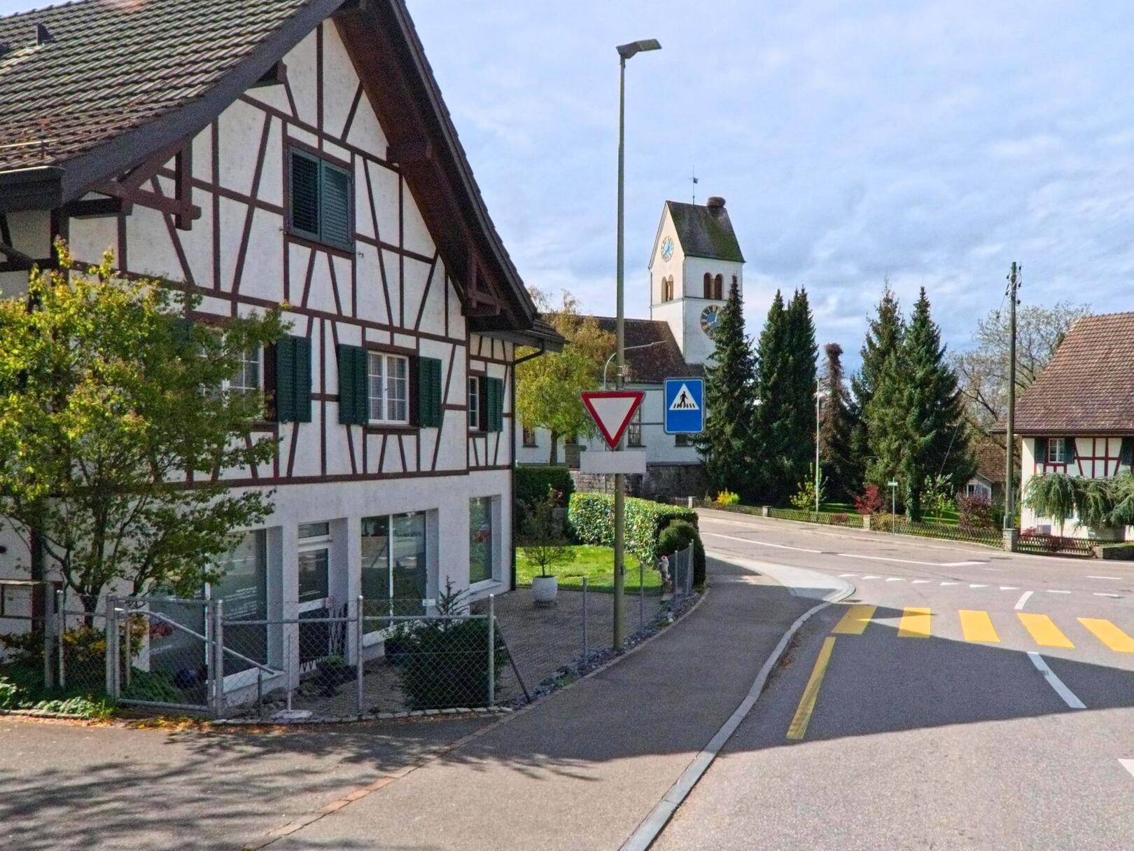 Im Ortszentrum von Steinmaur (8162, Kanton Zürich) stehen traditionelle Fachwerkhäuser neben der reformierten Kirche, die mit ihrem Turm das Dorfbild prägt.