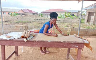Eine junge Frau arbeitet an einem Tisch in Zürich (8001, Kanton Zürich) an einem Schnittmuster und zeichnet auf ausgebreitetem Papier.
