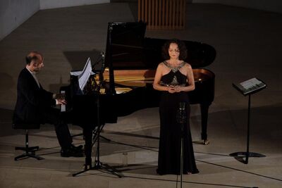 Eine Saengerin steht vor einem Konzertflügel, waehrend ein Pianist sie bei einer Darbietung in Liestal (4410, Kanton Baselland) musikalisch begleitet.